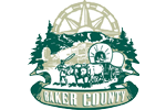 Baker County logo is drawing of pioneer family in covered wagon pulled by oxen traveling through forested area.